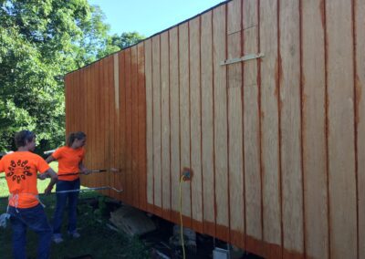 two people painting the wood walls